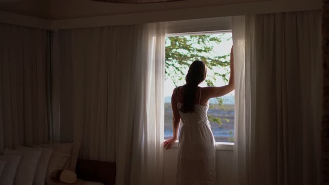 Young woman looking through hotel window