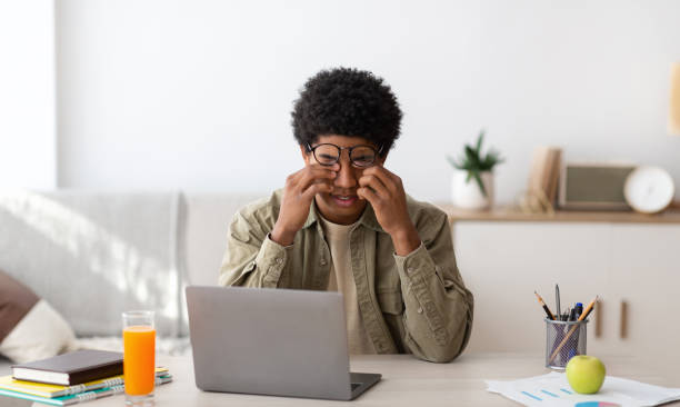 istock Tired black guy rubbing his eyes while studying online on laptop at home, panorama 1284082231