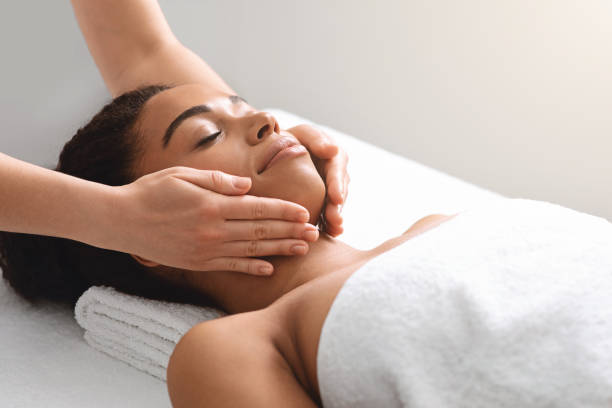istock Masseuse hands massaging relaxed black lady face 1284083317