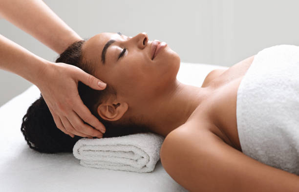 istock Female masseuse massaging relaxed black lady head 1284084360