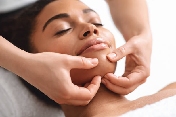istock Massage therapist rubbing relaxed black lady chin 1284084635