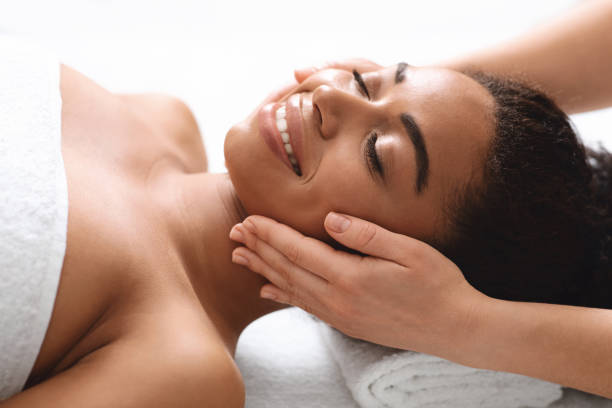 istock Smiling black woman having lifting face massage at spa 1284084781