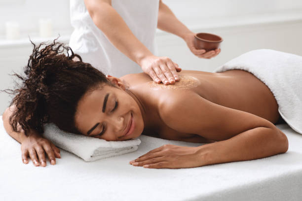 istock Spa therapist applying exfoliating mask on black woman body 1284084892