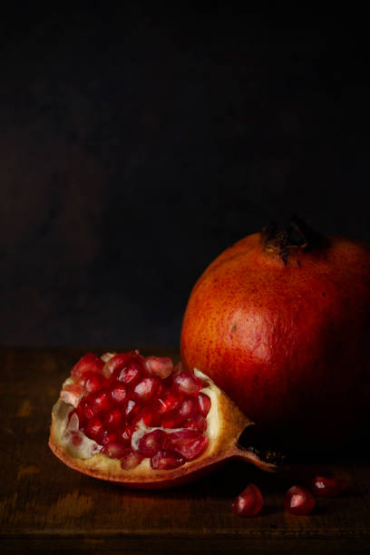 istock A whole pomegranate with a quarter to one side. Side lighting with dark blue background 1284086529