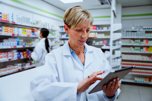 istock Caucasian female pharmacist scrolling on digital tablet standing concentrating in pharmacy 1284088053