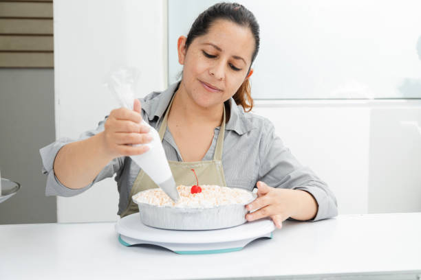 ケーキを飾る彼女のパティスリーのヒスパニックの女性 - 焼きたてのケーキにホイップクリームを置く女性 - 進取の女性 - bread bakery women cake ストックフォトと画像