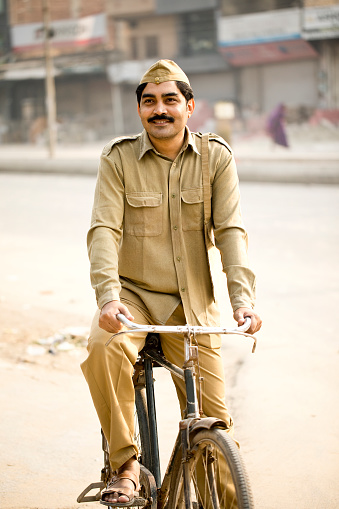 Male postal worker in uniform holding bicycle handlebar on street