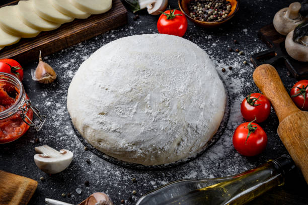 istock Ingredients for making pizza dough, mozzarella cheese, tomatoes, mushrooms, olive oil and basil on a black background, close up 1284092904