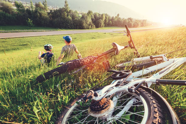 istock Father and son rest together in high green grass after bicycle walk 1284095530