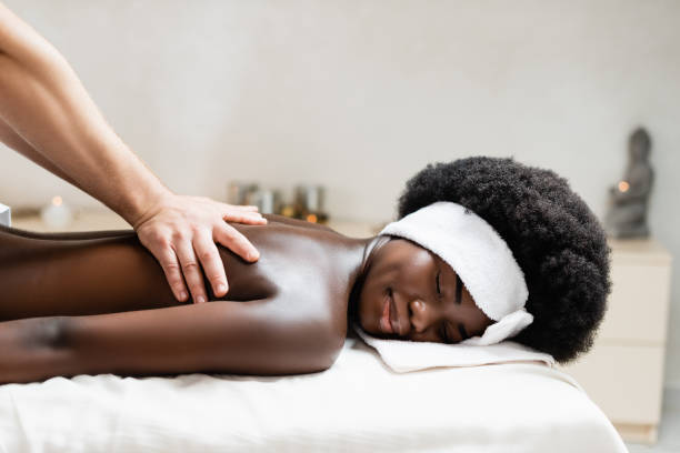Masseur massaging african american woman on massage table in spa salon on blurred background Masseur massaging african american woman on massage table in spa salon on blurred background black male massage stock pictures, royalty-free photos & images