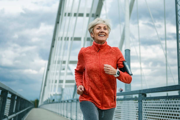 улыбаясь зрелая женщина работает - senior adult running jogging senior women стоковые фото и изображения