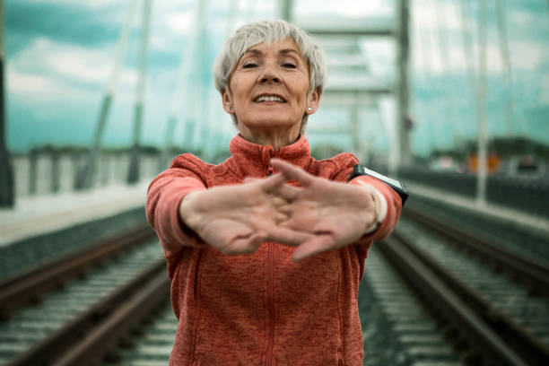 Mature woman stretching arms on a bridge getting ready for running