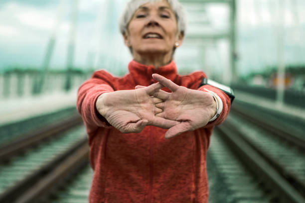 istock Mature woman stretching arms on a bridge getting ready for running ,focus on palms 1284097735