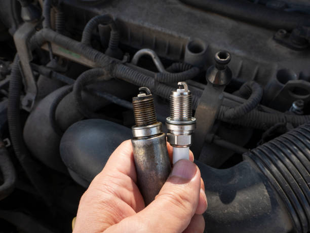 istock Man Holding old and new car spark plugs on engine background 1284099293