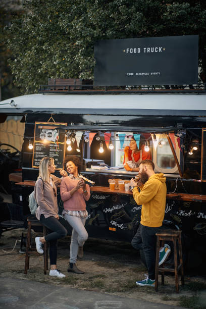 istock vertical image of multiethnic young people socializing while eating outdoor in front of modified truck for fast food 1284099561