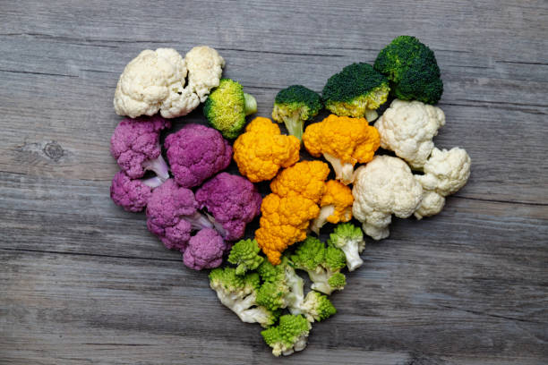 Cauliflower and romanesco broccoli on wooden background. Healthy food concept. Heart made of cauliflower and romanesco broccoli on wooden background. Healthy food concept. fractal plant cabbage textured stock pictures, royalty-free photos & images