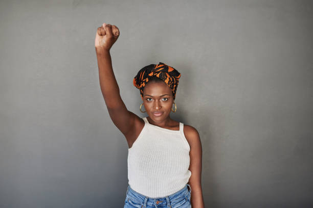 I fully support the cause Studio portrait of a young woman raising her fist against a grey background racial equality photos stock pictures, royalty-free photos & images