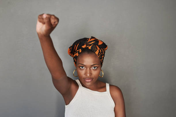 Always stand by what you believe in Studio portrait of a young woman raising her fist against a grey background racial equality photos stock pictures, royalty-free photos & images