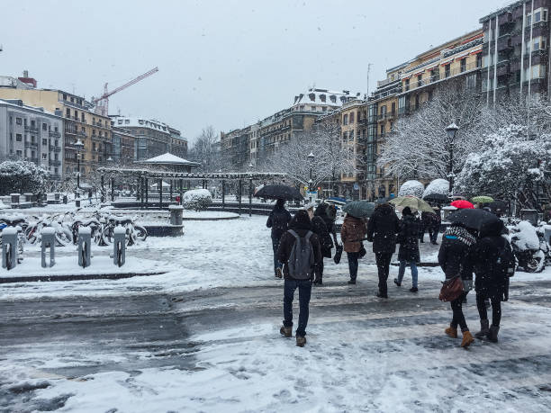istock Unrecognizable people with umbrellas walking in a snow covered street 1284104448