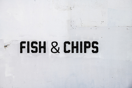 Restaurant pub menu sign on street white building wall outside closeup with black text for fish and chips food