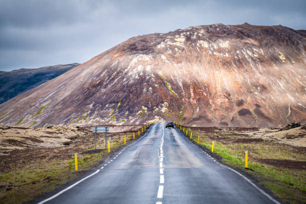 campo de lava en la península de snaefellsnes en islandia sin nadie en el punto de vista del coche de carretera recto y acantilado rocoso en el día nublado - snaefellsnes fotografías e imágenes de stock