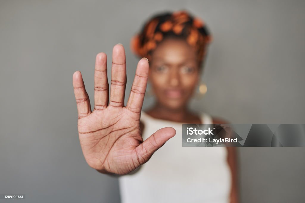 Don't take a step closer Studio portrait of a young woman holding her palm out against a grey background Stop Gesture Stock Photo