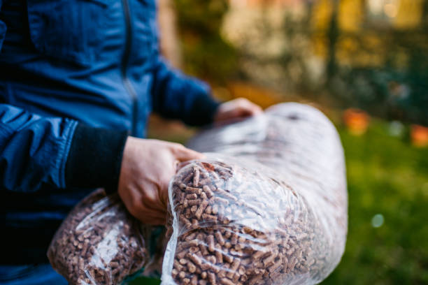 Carrying bag of pellets Young Caucasian man Loading wheelbarrow with bags of pellets. granule stock pictures, royalty-free photos & images