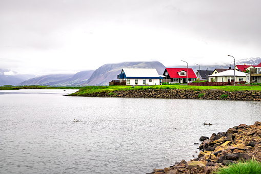 Landscape view of small village by fjord water river and mountains in small fishing town called Hofn in Iceland