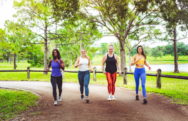 Group of women power walking outdoors Group of athletic women walking outdoors yoga pants photos stock pictures, royalty-free photos & images