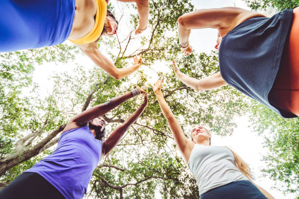 group of female athletes high five with hands in a circle - exercising motivation looking up african descent imagens e fotografias de stock