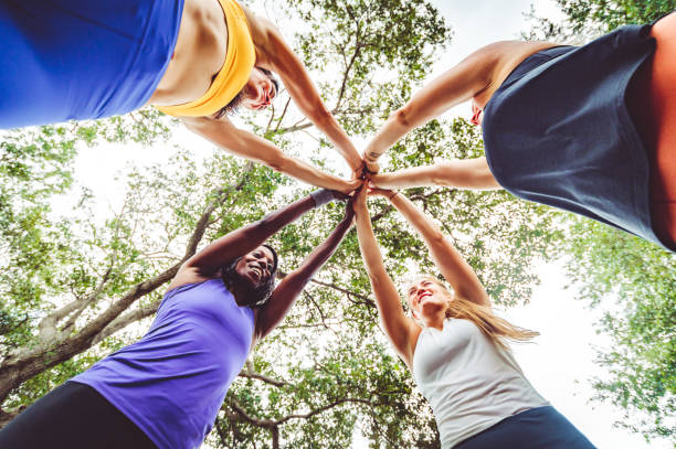 grupa zawodniczek łączy ręce w kręgu - exercising motivation looking up african descent zdjęcia i obrazy z banku zdjęć