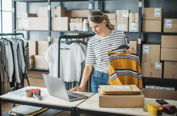Woman running online clothing store Mature woman at online shop. She is owner of small online shop. Receiving orders and packing boxes for delivery. labeling photos stock pictures, royalty-free photos & images