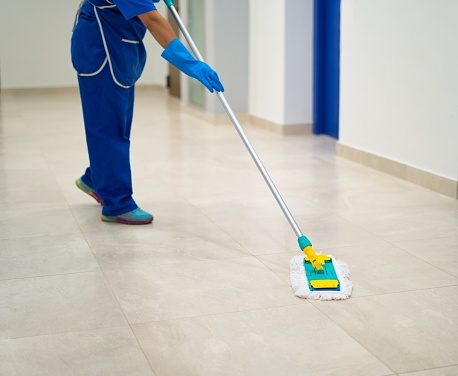 A cleaning lady cleans the hallway with a mop