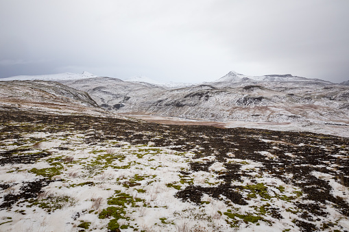 Landscape of hills covered in snow on the Snaefellsnes Peninsula under a cloudy sky in Iceland
