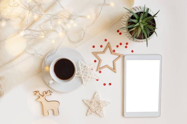 istock Christmas decorations and a digital tablet with a blank screen, lies on a white table with a glowing garland 1284117598