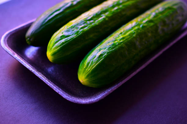 Green ripe cucumbers in a package on a black background