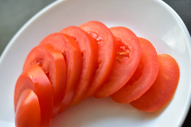 Photo of sliced tomato over a kitchen  sink.