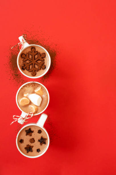 istock White cups with hot chocolate and marshmallows, and cocoa powder decor snowflake and stars shape on red background with copy space 1284119191