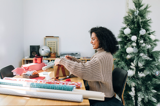 Getting Ready for Christmas: a Happy Young Woman Packing Christmas Presents for her Loved Ones (Copy Space)
