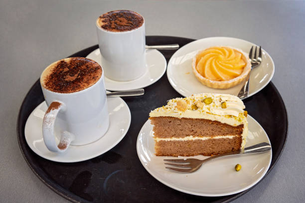 Morning tea of a layered cake with lemon tart and coffee on a tray
