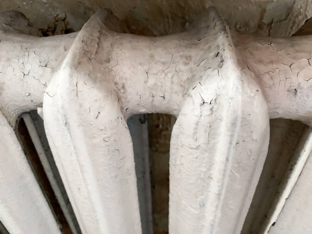 istock White cracked paint on an old cast-iron radiator with bobweb, spiderweb in an apartment needed to be replaced or repared 1284123377