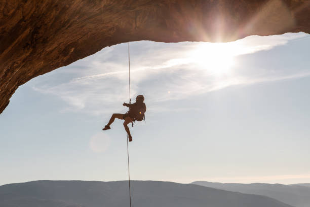 istock Male rock climber hanging on natural arch 1284124924