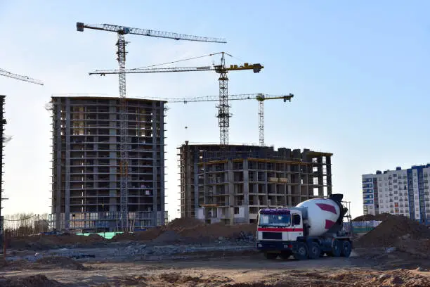 Photo of Cement  mixer truck working pouring mix into crane concrete bucket