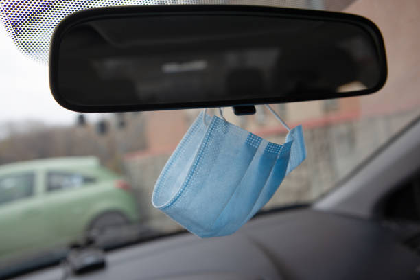 istock Medical face mask hanging on rear view mirror inside the car. for protect himself from bacteria and virus while driving a car. 1284128093