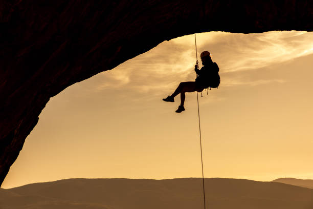 istock Male rock climber hanging on natural arch 1284128539