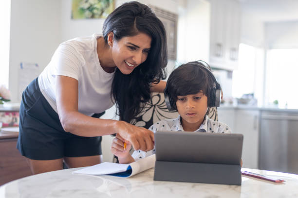 istock Mother helping elementary age son with online school assignment during COVID-19 1284133755