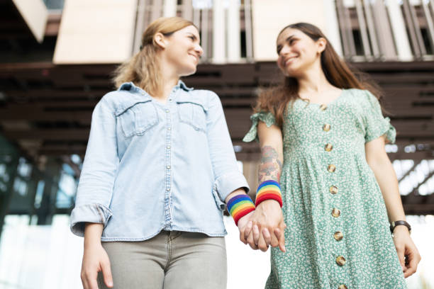 istock Young girlfriends holding hands with rainbow bracelets 1284137918