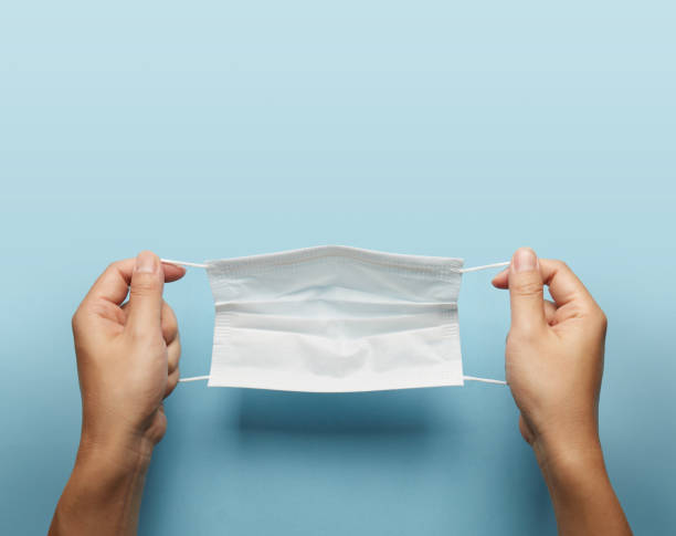 istock A man holding face mask over blue background. 1284139687