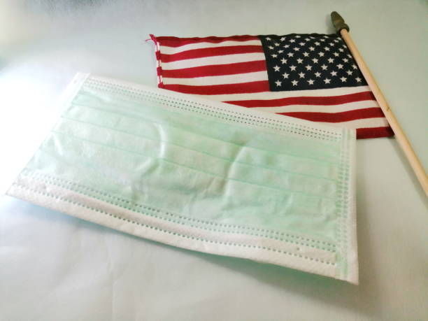istock American flag and face mask on white desk 1284144519