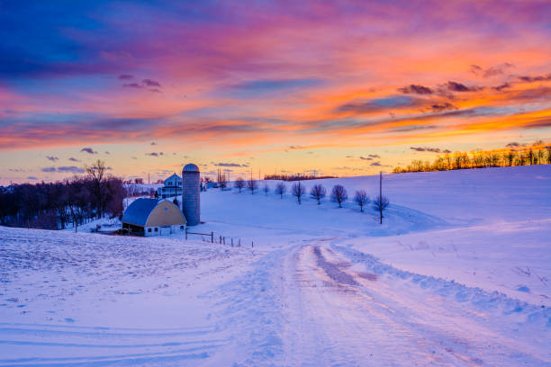 Sunset over a snow covered road and a farm in a rural area of York County, Pennsylvania stock photo